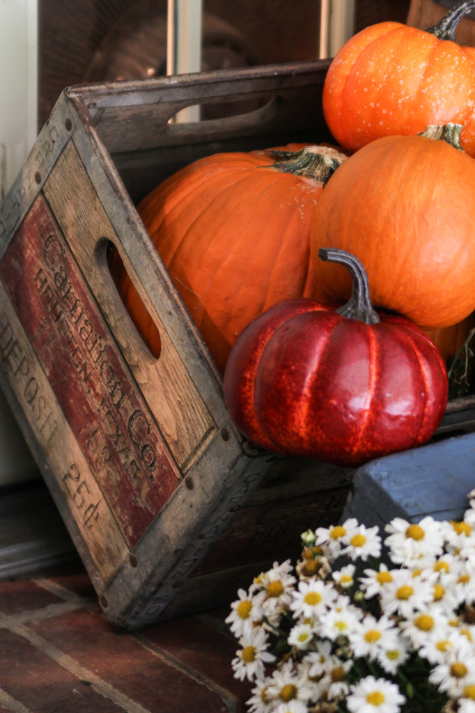 An old carnation milk crate hold pumpkins on the porch