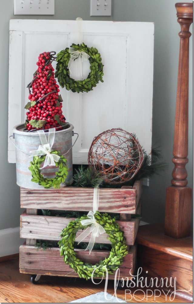 Pretty rustic Christmas vignette with boxwood wreaths and a cranberry topiary in a minnow bucket.