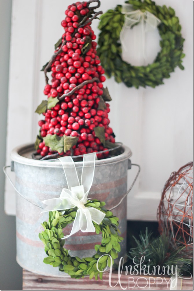 Pretty rustic Christmas vignette with boxwood wreaths and a cranberry topiary in a minnow bucket.