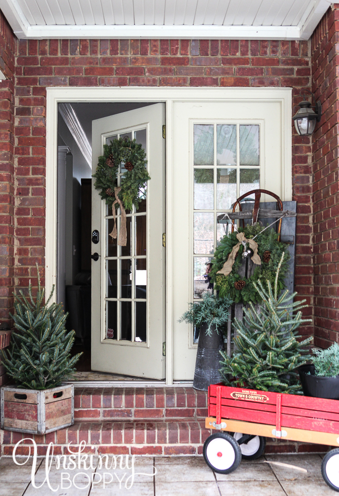 Pretty back porch decorated for Christmas with vintage Radio Flyer wagon and an old sled.