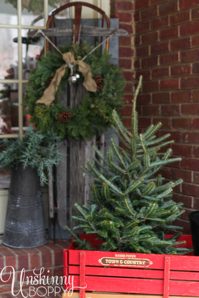 Pretty back porch decorated for Christmas with vintage Radio Flyer wagon and an old sled.