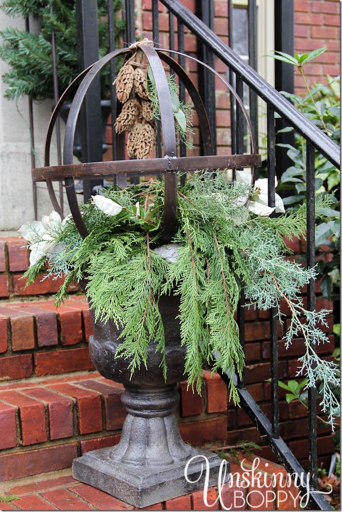 Fill an urn with evergreen branches and a metal orb with magnolia blossom cones hanging inside