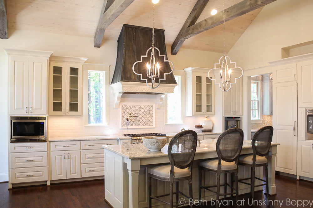 French country kitchen with ceiling beams and wooden vent hood