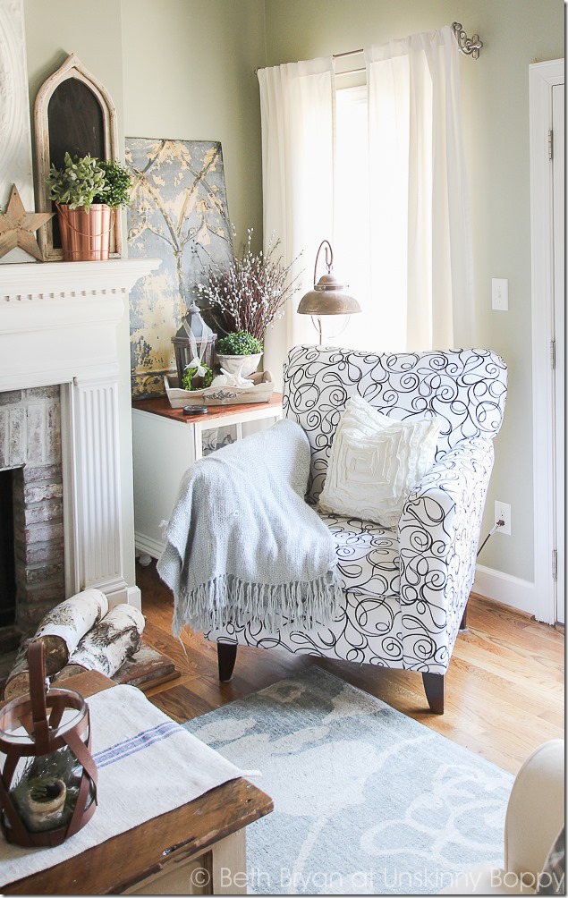 Love the swirly black and white fabric on that side chair.  The copper lighting and mantel decor, the pressed tin piece- love