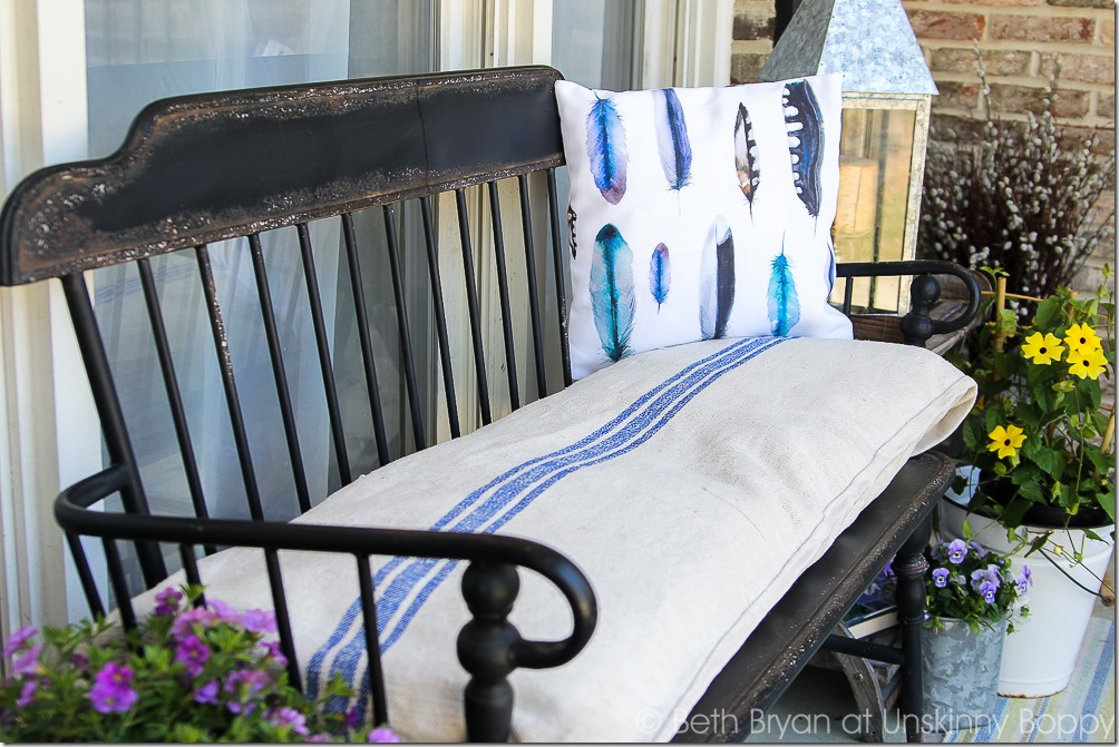 Black metal Front porch bench with watercolor feather pillow, french grain sack cushion and flowers in a bucket for Spring | Cozy Spring Home Tour | www.unskinnyboppy.com