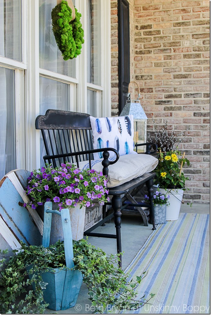 Black metal Front porch bench with watercolor feather pillow, french grain sack cushion and flowers in a bucket for Spring | Cozy Spring Home Tour | www.unskinnyboppy.com