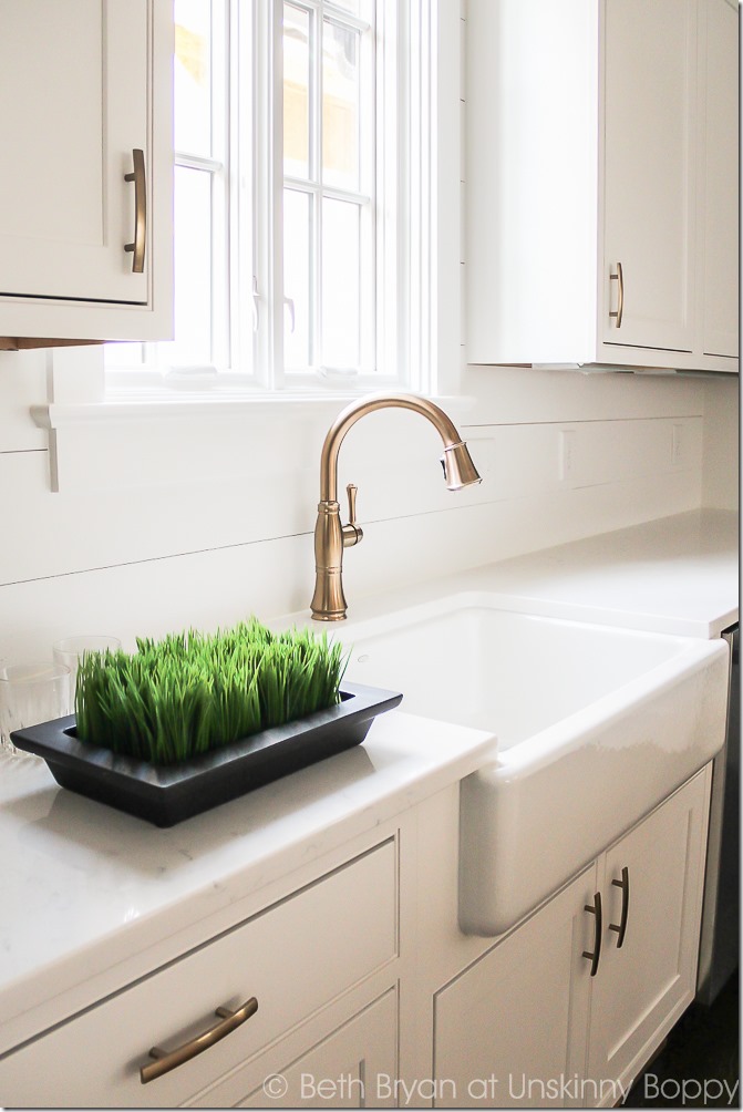 aged bronze kitchen faucet in white kitchen with shiplap