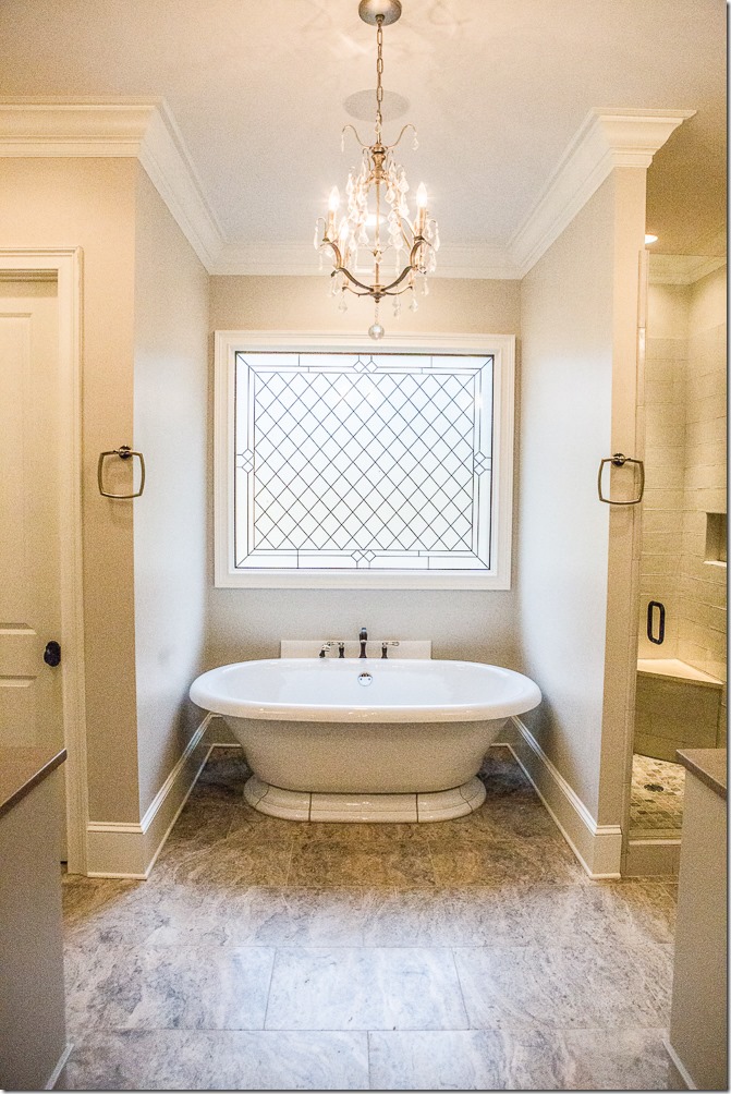 freestanding bathroom tub with leaded glass window and chandelier