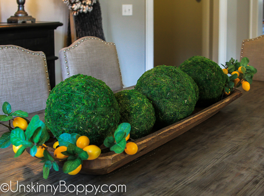 Moss balls and lemon stems in a dough bowl on dining table centerpiece