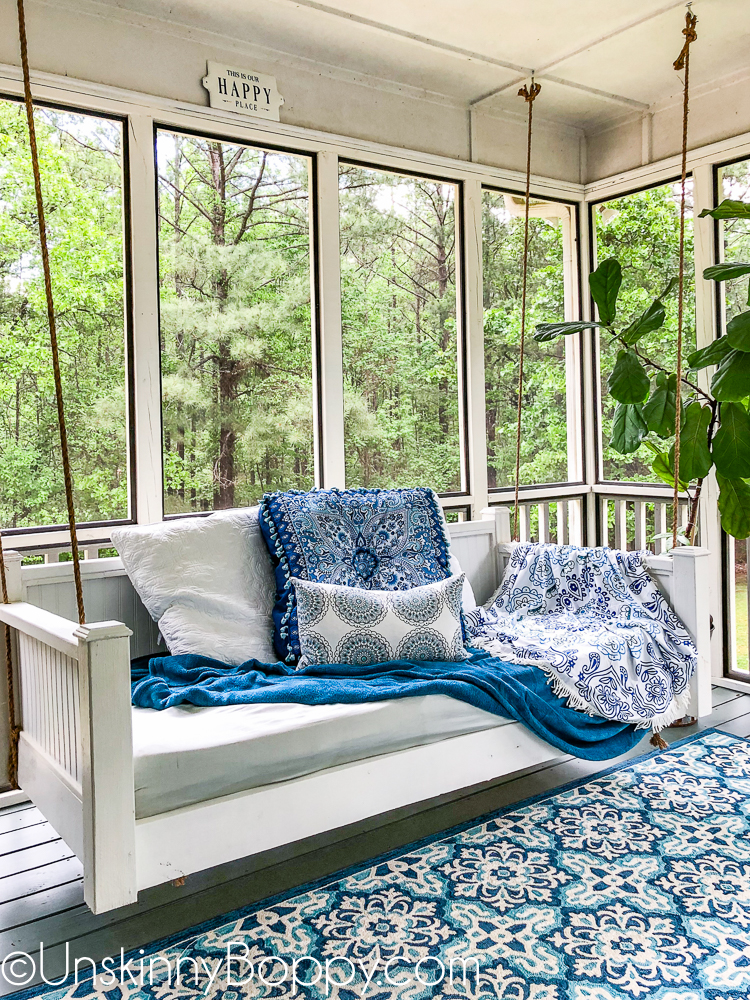 White beadboard porch swing bed with blue decor accents
