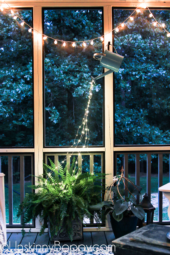 Watering can with fairy lights pouring out at night on a cozy back porch