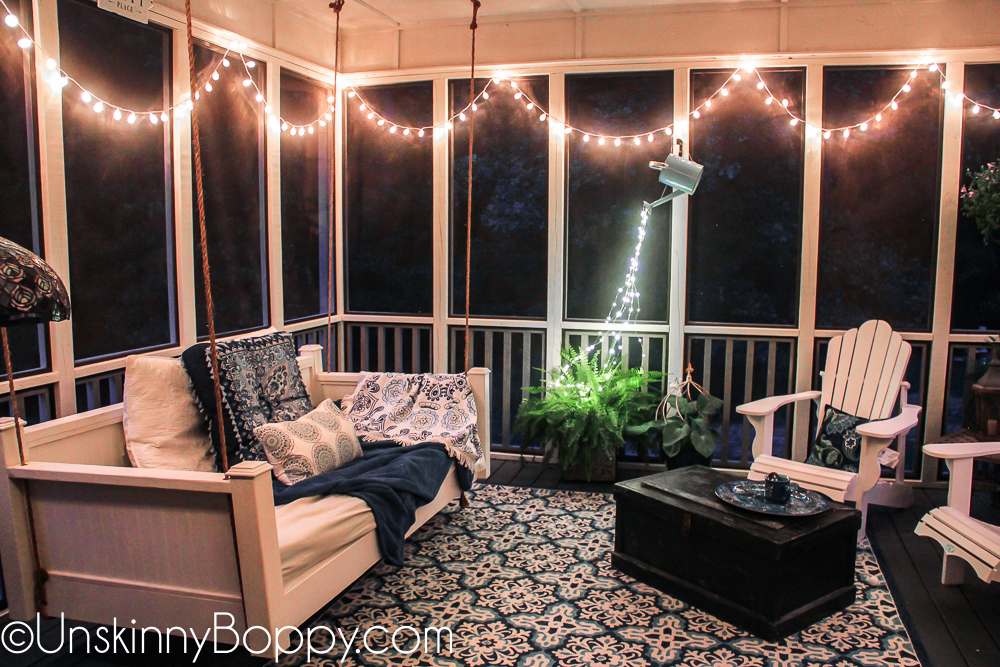 Cozy back porch with strings of lights and bed swing