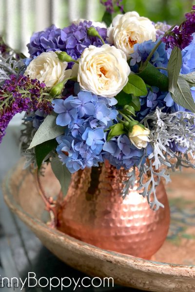 Periwinkle Hydrangea and white rose bouquet in a copper pitcher