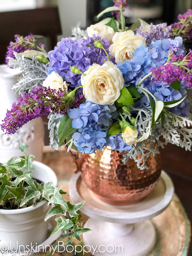 Periwinkle Hydrangea and white rose bouquet in a copper pitcher