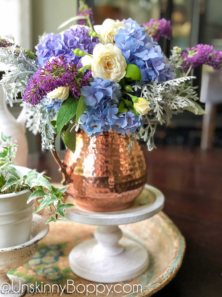 Periwinkle Hydrangea and white rose bouquet in a copper pitcher