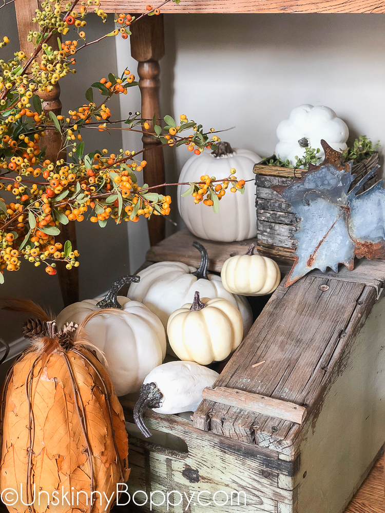 white pumpkins in a green box with pyracantha berries