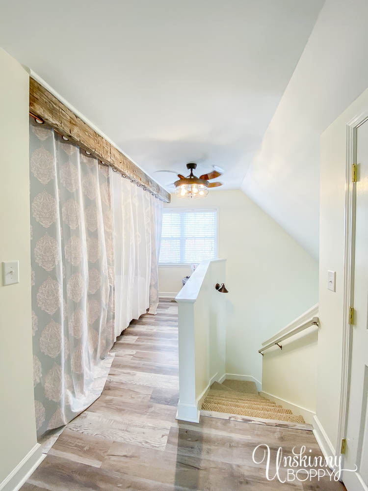 Curtains on loft behind hand-hewn beam