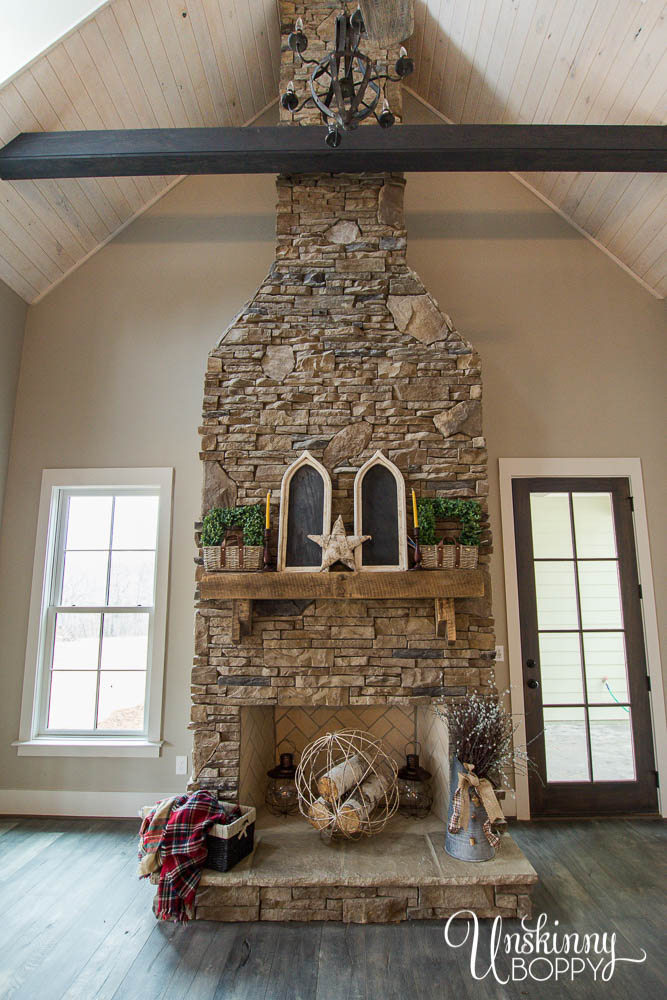 two-story fireplace with stacked stone and rustic mantel