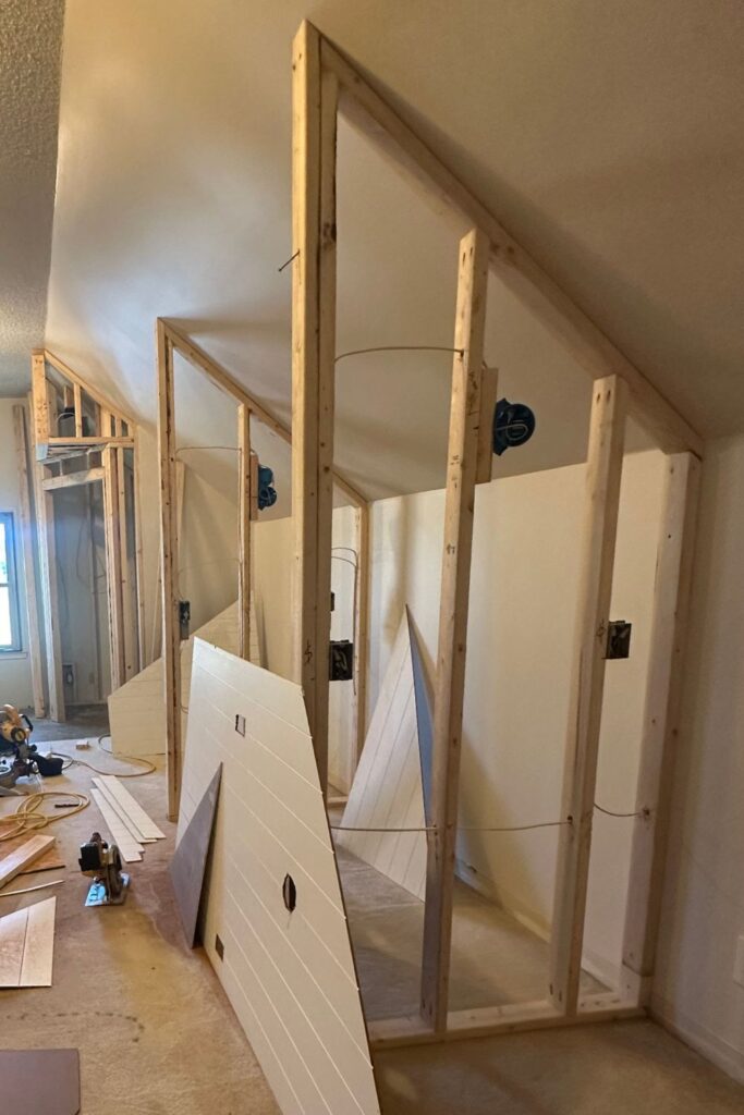 2x4 framing construction of attic bunk room divider walls set 16 inches on center with ladder in center walkway during early build stage